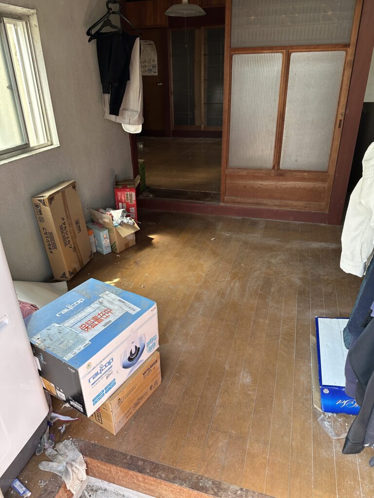 同じ室内の片付け後。荷物が減り、床面と奥の部屋への通路が見える様子。